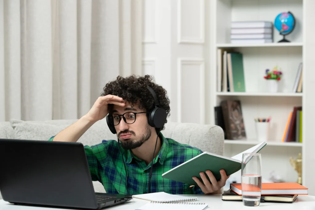 student online cute young guy studying computer glasses green shirt confused holding head 1