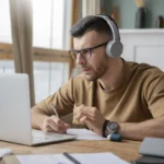 Student studying advanced English course online using laptop and headphones